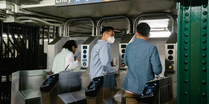 People using turnstiles at a subway station entry in urban setting.